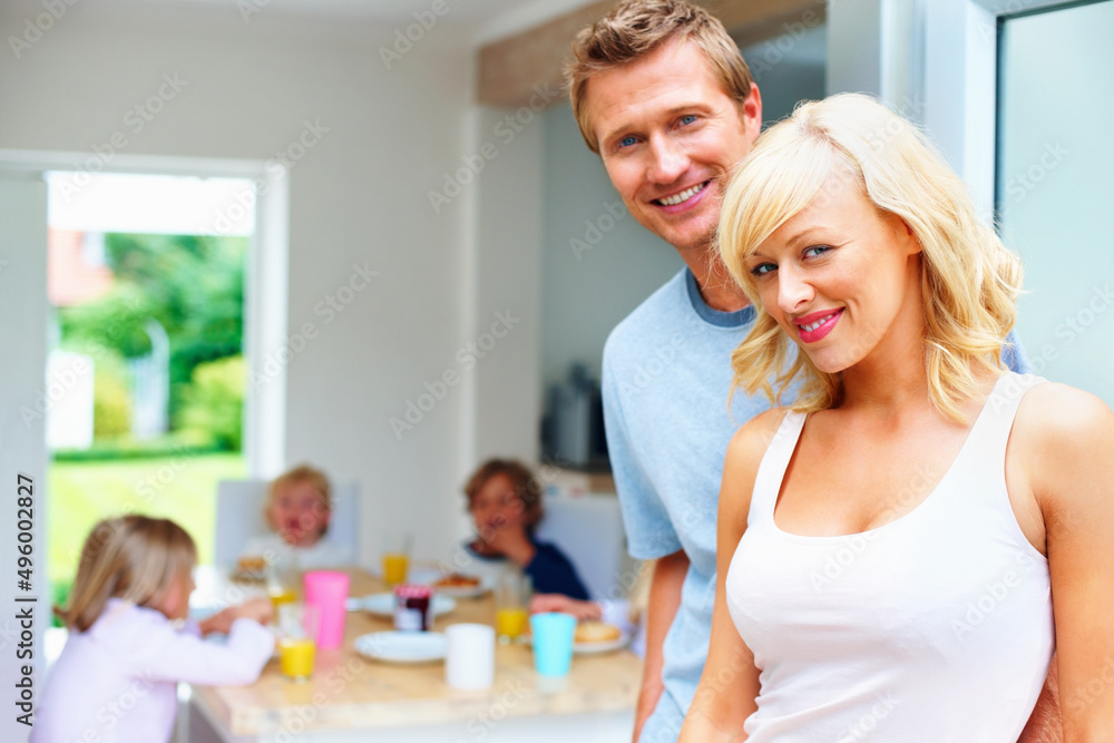 Mature couple with their children having breakfast in background. Portrait of a happy mature couple with their children having breakfast in background. Mature couple with their children having breakfast in background. Portrait of a happy mature couple with their children having breakfast in background.
