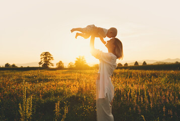 Loving mother and baby at sunset. Beautiful woman and small child in nature background. Concept of natural motherhood. Happy healthy family at summer outdoors. Positive human emotions and feelings.
