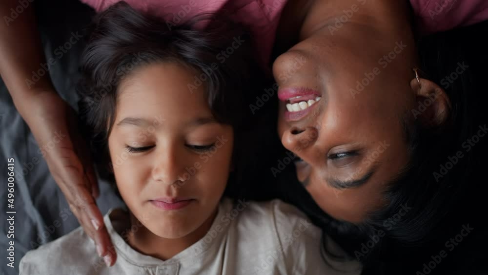 Overhead view of indian mother lying on bed with her little son at home. Overhead view of indian mother lying on bed with her little son at home.