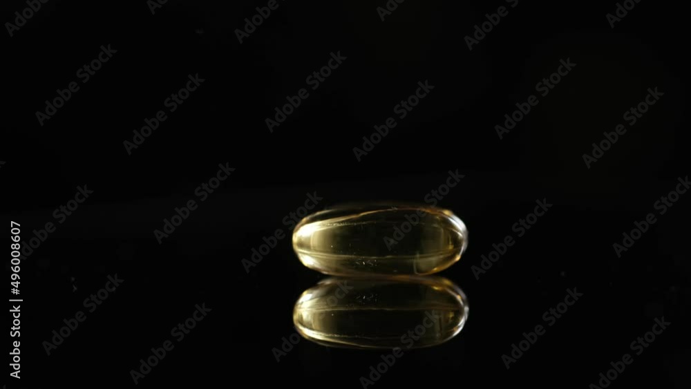 Omega 3 Gold oil capsules on black background, rotation. Close-up of rotating golden pills.Vitamins supplements pills omega 3. Cod liver oil medicines. Fish oil capsules.Omega 3 Fish oil vitamin gel Omega 3 Gold oil capsules on black background, rotation. Close-up of rotating golden pills.Vitamins supplements pills omega 3. Cod liver oil medicines. Fish oil capsules.Omega 3 Fish oil vitamin gel
