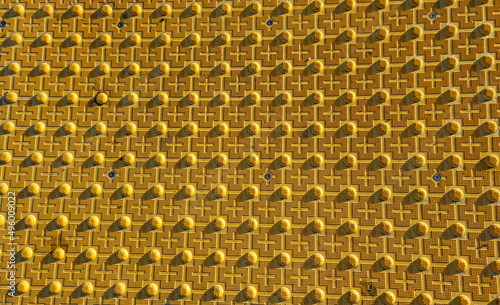 Textured yellow metal surface with bumps  crosses  honeycomb pattern  distinctive background for conceptual messages.
