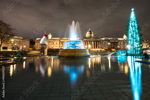 Christmas decorations and menorah in Trafalgar Square in London. Long exposure shot with blurred water and reflections: London, England- December 20,2021