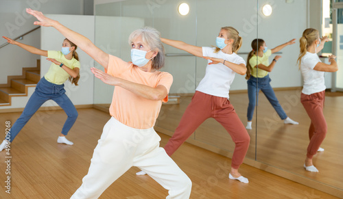 Family in protective masks are engaged in sports dancing in the gym