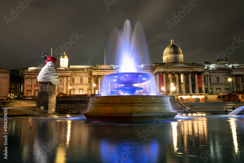 Christmas decorations and menorah in Trafalgar Square in London. Long exposure shot with blurred water and reflections: London, England- December 20,2021