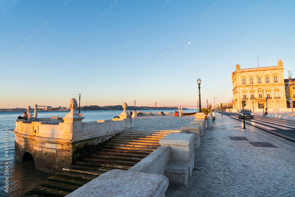 Obraz premium Ribeira das Naus promenade overlooking the 25 de Abril bridge over the Tajo River in Lisbon. Portugal 