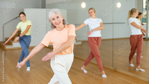 Elderly woman learning aerobic dance with her younger relatives in studio. © JackF