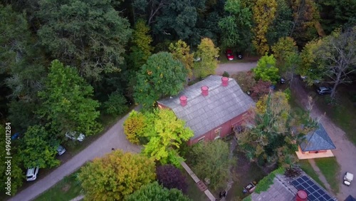 Aerial top down dolly out over modern house hidden between autumnal colorful woods at daytime, cars parked. Bloomsburg, Pennsylvania, USA. photo