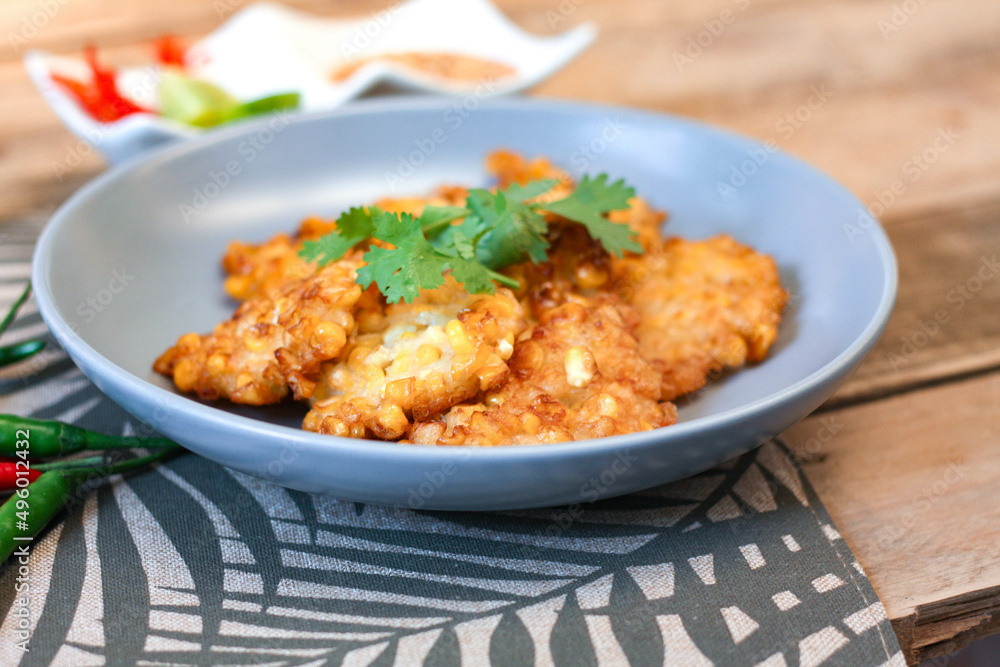 Corn Fritters With chili sauce placed on a wooden table Corn Fritters With chili sauce placed on a wooden table