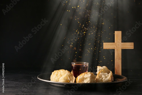 Foto Glass of wine, bread and cross on dark background