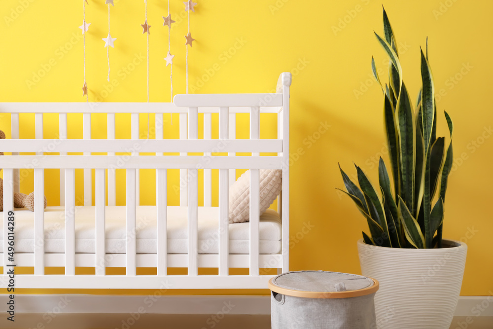 Modern children's room with comfortable crib near color wall Modern children's room with comfortable crib near color wall