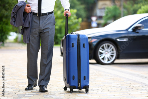 Fotografie, Obraz Young businessman with blue suitcase walking outdoors