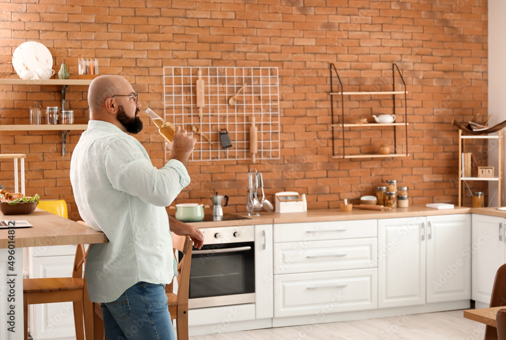 Bald man drinking beer in kitchen Bald man drinking beer in kitchen