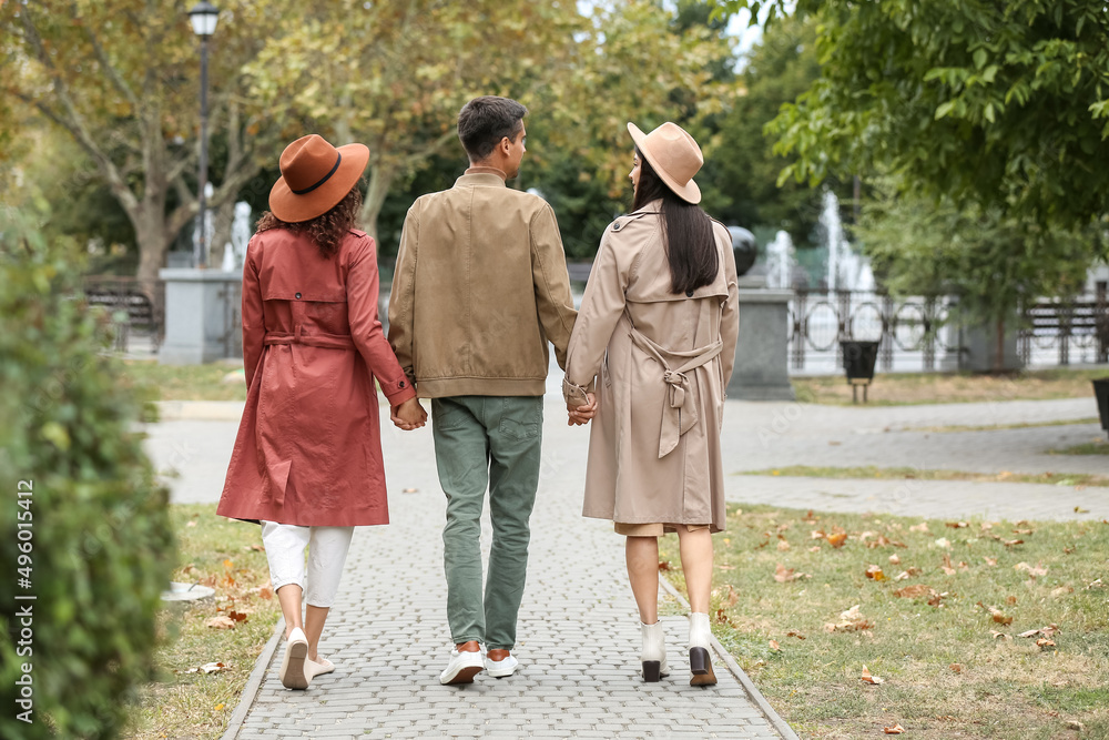Man with two beautiful women walking in park. Polyamory concept Man with two beautiful women walking in park. Polyamory concept
