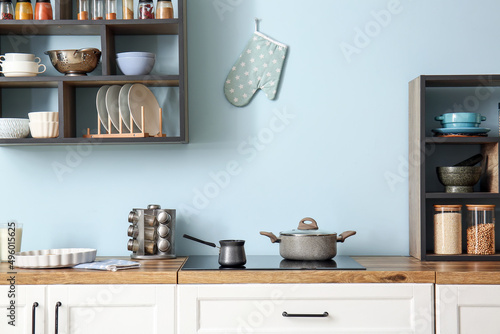 Stove with cooking pot and cezve near blue wall in kitchen © Pixel-Shot