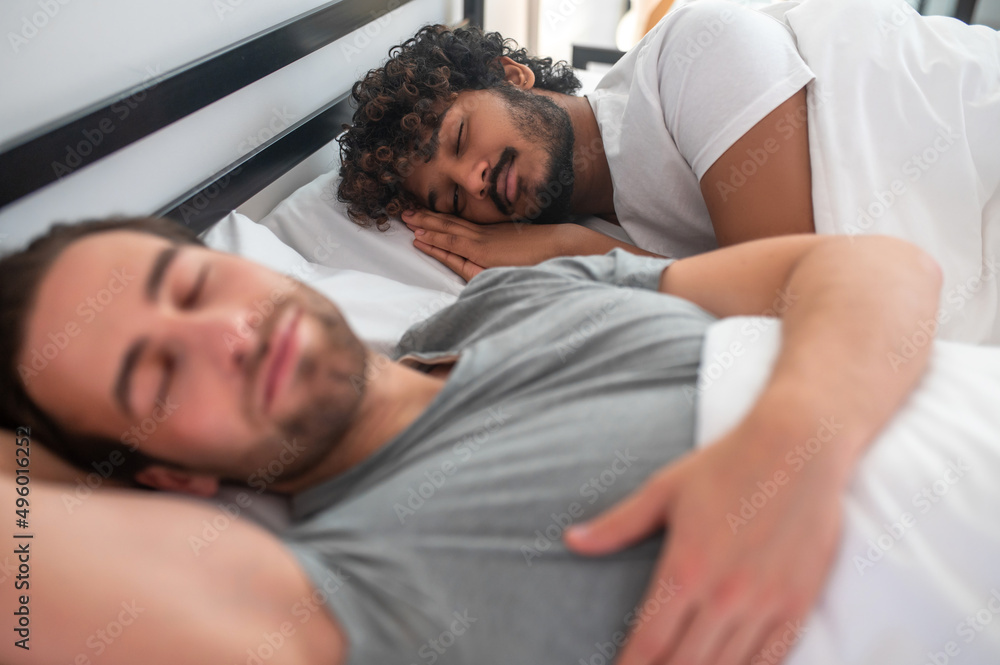 Gay couple lying taking a nap in their bedroom Gay couple lying taking a nap in their bedroom