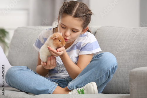 Little girl with cute guinea pig on sofa photo