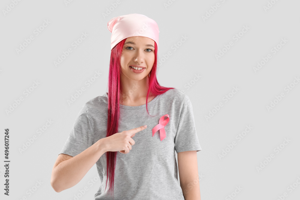 Young woman with pink ribbon on light background. Breast cancer awareness concept Young woman with pink ribbon on light background. Breast cancer awareness concept