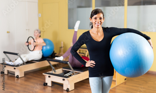 Portrait of a positive and confident latin american woman standing in a fitness studio with a fitball in her hands