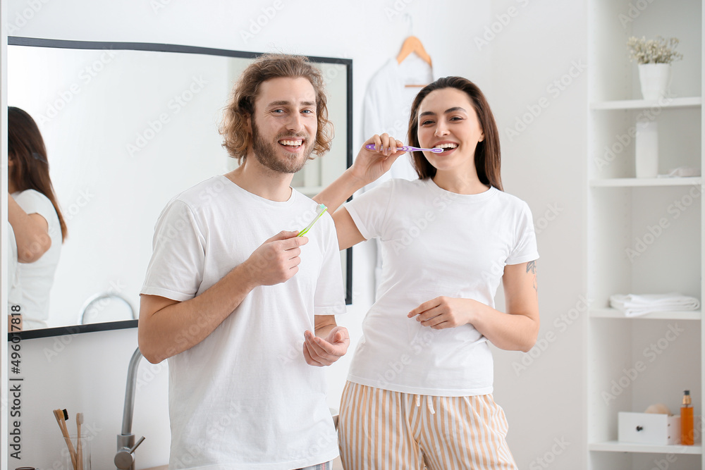 Fototapeta premium Lovely young couple brushing teeth in bathroom