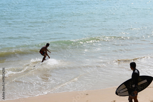 Two Man on a skimboard catching a wave in a beach in Aonang, Krabi ,Thailand. photo