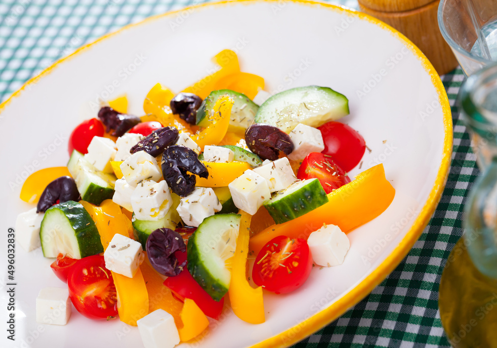 Plate of tasty Greek salad with fresh cucumbers, tomatoes, bell pepper and feta cheese