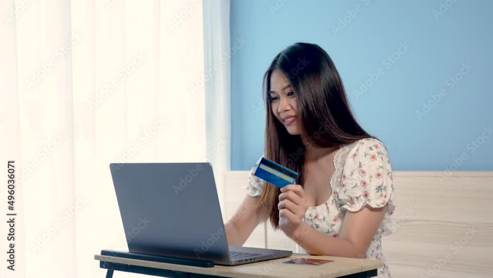 4K 50fps,Beautiful Asian girl, wearing a white floral shirt, having a happy expression, after successfully paying for an online purchase via a laptop computer , online shopping. 4K 50fps,Beautiful Asian girl, wearing a white floral shirt, having a happy expression, after successfully paying for an online purchase via a laptop computer , online shopping.