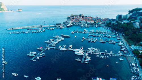 Aerial top down view of boat dock and yacht port in Budva, Montenegro. White private motor boats are moored to pier on Adriatic sea coast. Yacht club boats parking. Photo from drone.