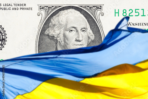 ukrainian national flag on foreground and US one hundred dollars paper currency on background. ukraine investment concept photo