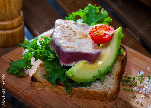 Toasted bread with tuna steak, salad, avocado and cherry tomato