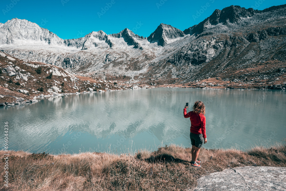 hiker taking a photo in front of a lake the mountains