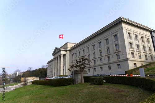 Federal supreme court of Switzerland with stairway at City of Lausanne on a cloudy spring day with waving Swiss flag. Photo taken March 18th, 2022, Lausanne, Switzerland.
