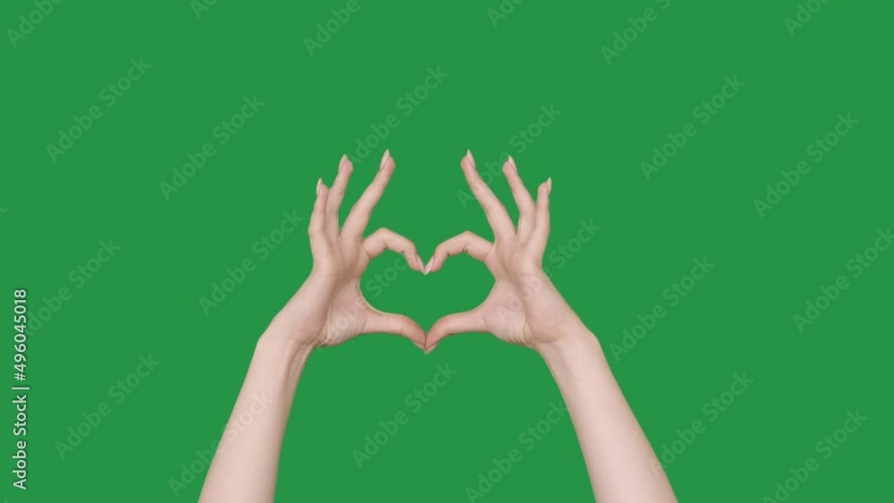 Love sign. Thanks gesture. Gratitude appreciation. Positive feeling. Female hands showing finger heart shape isolated on green chroma key copy space background. Love sign. Thanks gesture. Gratitude appreciation. Positive feeling. Female hands showing finger heart shape isolated on green chroma key copy space background.