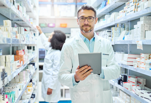 Its a pharmacists best friend. Shot of a mature man using a digital tablet to do inventory in a pharmacy.