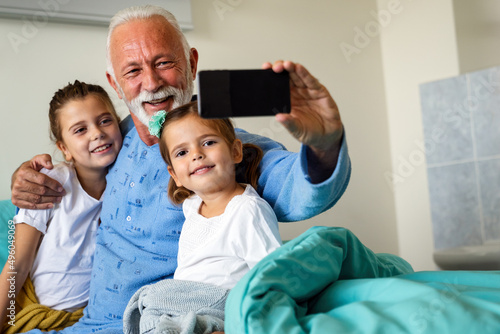 Happy laughing grandfather playing, having fun with his grandchildren together.