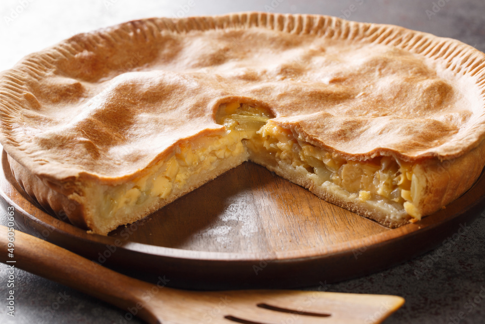 Rustic shortcrust pie with cheese and onion close-up in a plate on the table. Horizontal