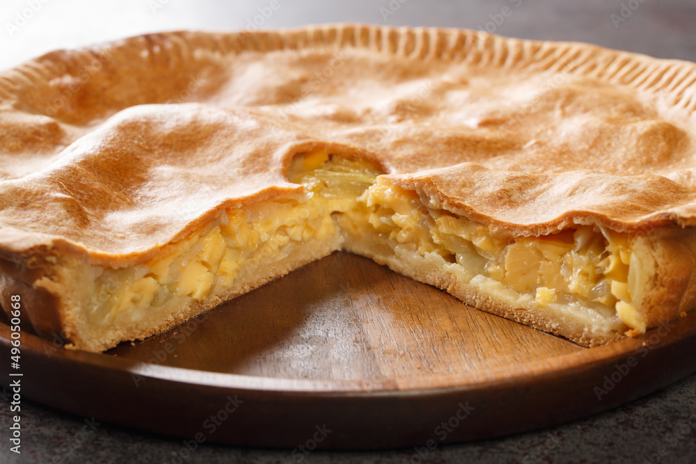 English closed pie with cheese and onions close-up in a plate on the table. Horizontal English closed pie with cheese and onions close-up in a plate on the table. Horizontal