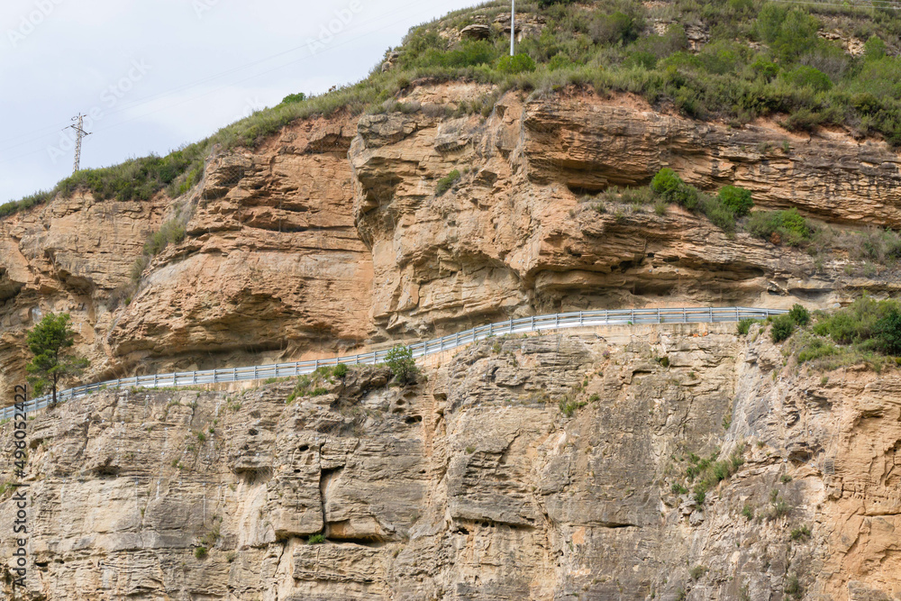 Highway with guard rails between a rocky mountain