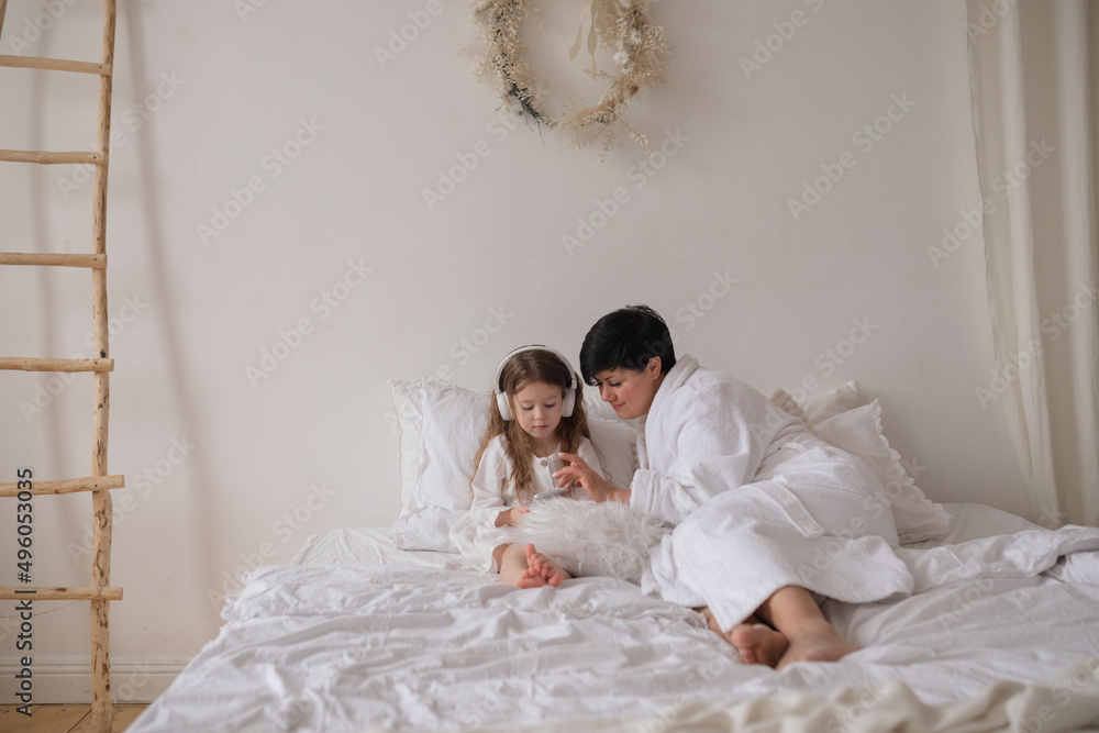 Mother and daughter using phone on the bed