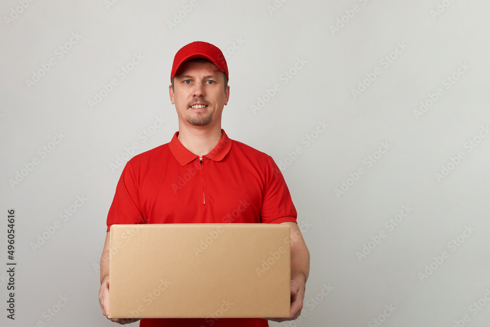 Young delivery man in red uniform standing with parcel box Young delivery man in red uniform standing with parcel box
