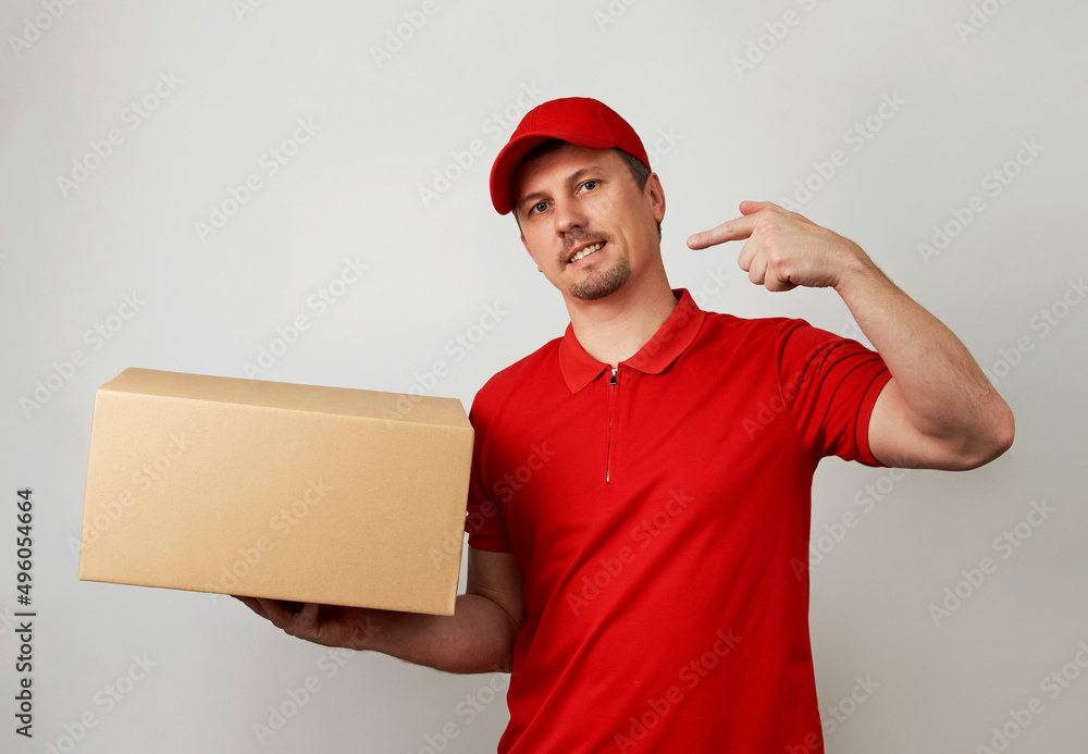 Young delivery man in red uniform standing with parcel box Young delivery man in red uniform standing with parcel box