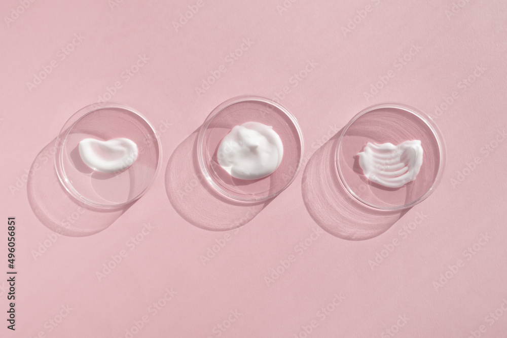 White cream textures in Petri dishes on a pink background. Concept of cosmetics laboratory researches. Smear of skincare cosmetics product. Wellness and beauty concept. Soft focus White cream textures in Petri dishes on a pink background. Concept of cosmetics laboratory researches. Smear of skincare cosmetics product. Wellness and beauty concept. Soft focus