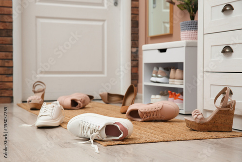 Stylish furniture and scattered shoes on floor in hall photo