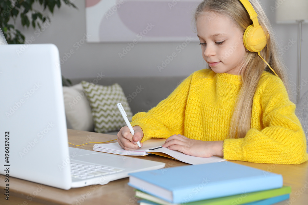 Cute little girl with modern laptop studying online at home. E-learning Cute little girl with modern laptop studying online at home. E-learning