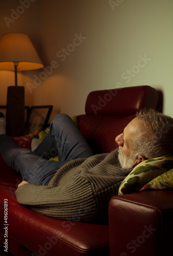 Adult man lying on sofa in living room at night