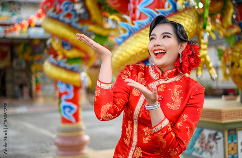 Asian beautiful woman wearing a cheongsam poses at shrine on Chinese New Year