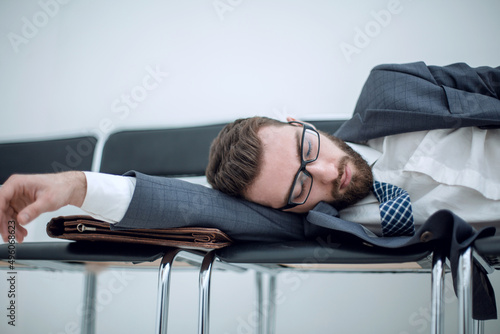 tired businessman sleeping on chairs in the office hallway