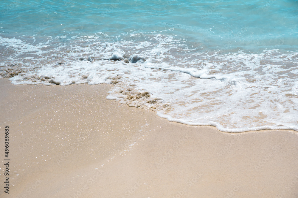 Soft blue oceans wave with foam and clear white sand. Tropical beach by the ocean  