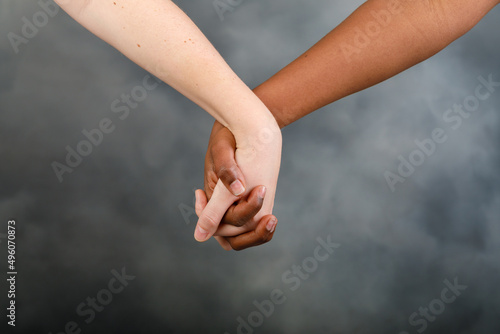 Lover hands, multiethnic couple. Grey background.