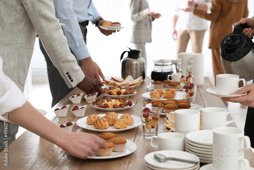 People near table with different delicious snacks during coffee break, closeup