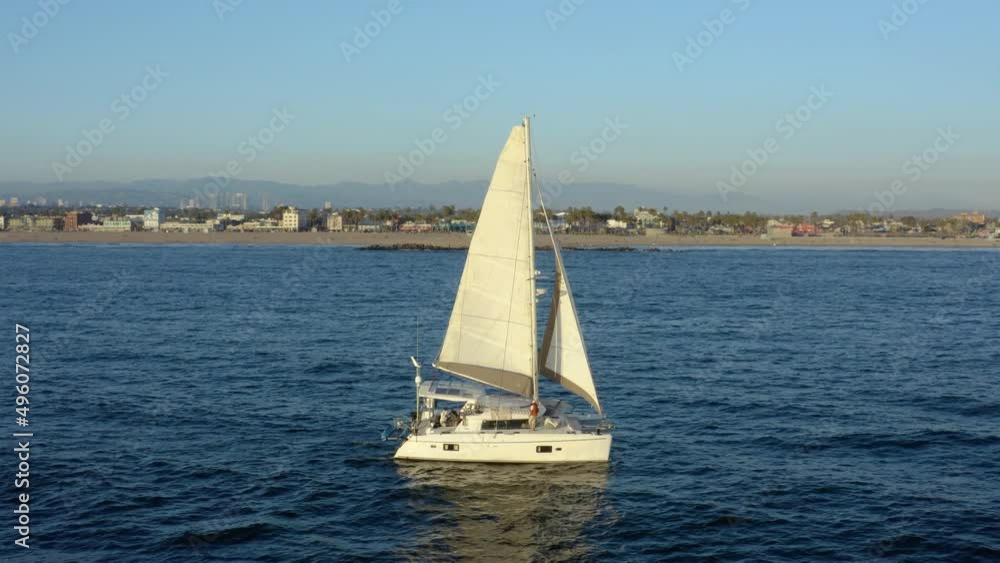 Sailboat in the ocean. White sailing yacht. Aerial view. sailboat floats in water by beautiful sunset. 4K Aerial drone point of view sailboat. Yacht sailing on open sea at windy day aerial. Sailboat in the ocean. White sailing yacht. Aerial view. sailboat floats in water by beautiful sunset. 4K Aerial drone point of view sailboat. Yacht sailing on open sea at windy day aerial.